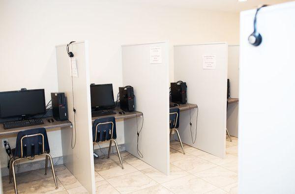 Test takers have their own cubicle, separated by partitions including a desktop. mouse, and headphones.