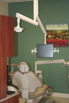 Modern dental treatment rooms with cable television overhead.