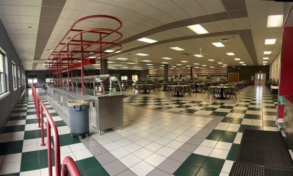 The cafeteria - fruit/salad bar, drink/coffee station on right side of this pic, warm food station on other side of tables & chairs.