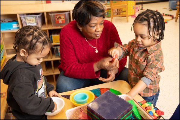 Teacher working with children in 3s classroom