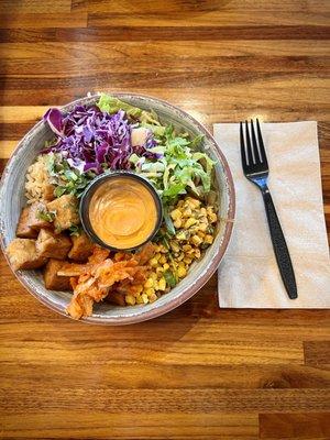 Custom bowl with half brown rice half greens and tofu. Magic sauce on the side.