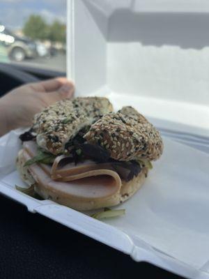 Bagel sandwich with turkey, lettuce, tomato, mayo, and on an everything bagel.