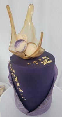 elegant Purple fondant cake with sugar sail filled with macaroons on top