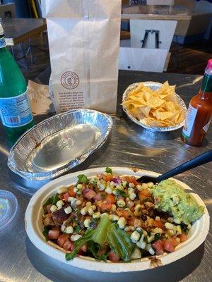 Chicken burrito bowl with guacamole and chips.