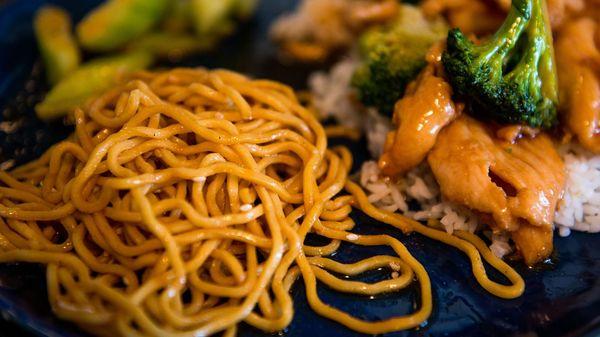 Sesame noodles in foreground. Sweet and sour cucumber; chicken and broccoli in background.