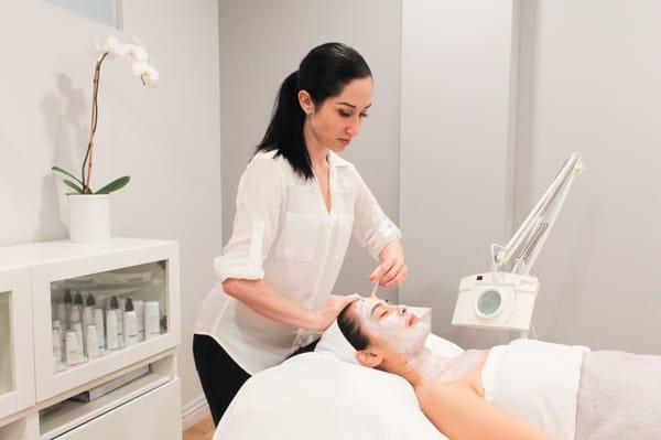 Brigitte applying a customized mask with fresh ayurvedic herbs to a clients skin to treat acne.