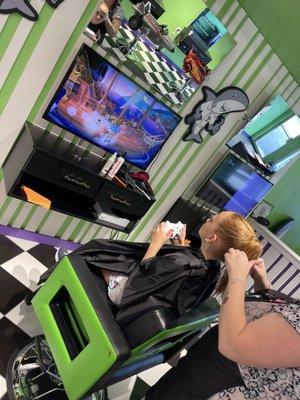 Finishing up hair styling in a bigger kid chair with video games Xbox.