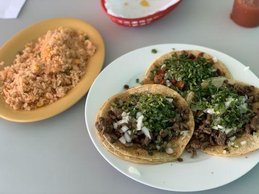 2 carne asada tacos and 1 al pastor taco with a side of rice.