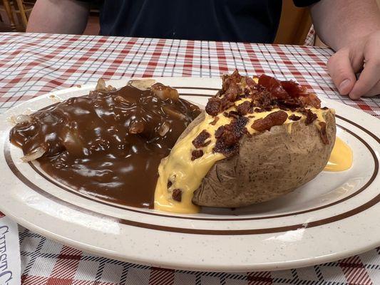 Hamburger steak with onions and gravy and a fully loaded baked potato (chili, cheese, and bacon).