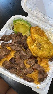 carnita frita with yellow rice, tostones, side of salad and avocado