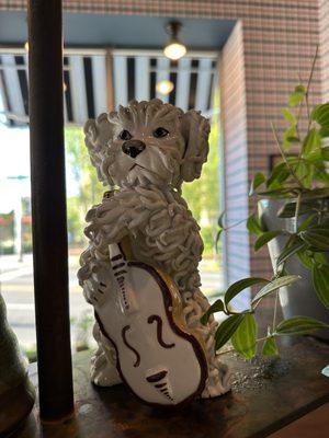 A statue of a puppy on the wall of plants