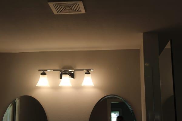 Proper venting and vanity lights complete a bathroom.