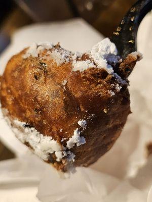 Close-up of a black plastic fork holding a fried Oreo.