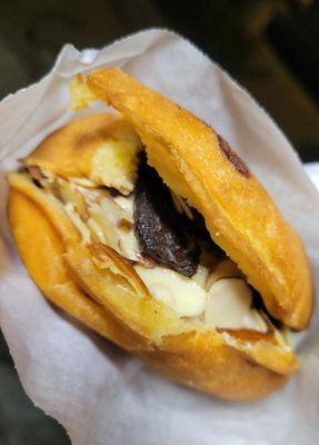 Donut bun with coffee ice cream, almonds & oreo cookie bites on top.