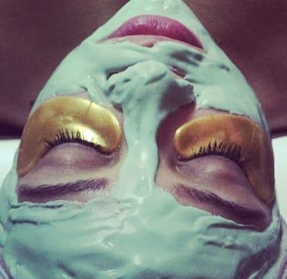 Client enjoying her luxurious 24k gold eye treatment and her cucumber mask.