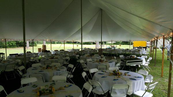 Pole Tent shown with round tables, linens and white folding chairs.