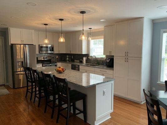 Modern white kitchen cabinets with beautiful granite countertop and glass backsplash tiles