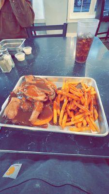 Roast beef platter white white bread and fries topped with brown gravy.