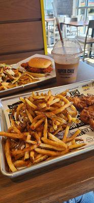 Regular fries and straps in front, loaded fries and buffalo sandwich in background