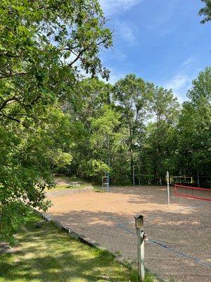 Two full sized sand volleyball courts nestled in the trees