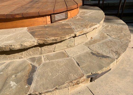 Stone steps with LED lighting lead to poolside redwood deck.