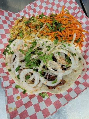 Kebabs with Tortita on the bottom and a side of rice, salad, onions, and a cilantro on the topping