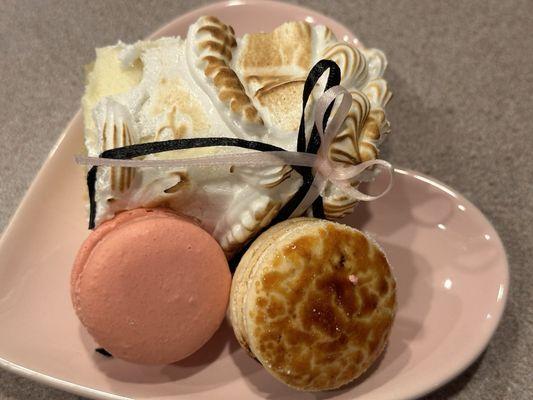 Slice of vintage meringue cake with white chocolate raspberry and creme brûlée macarons