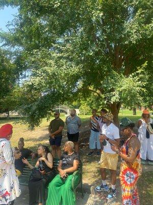 Some seated and some sitting get a lecture about all the goings on of Congo Square