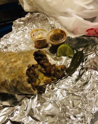 A traditional Mexican burrito with carne asada, pinto beans, onion, cilantro, and a delicious salsa.