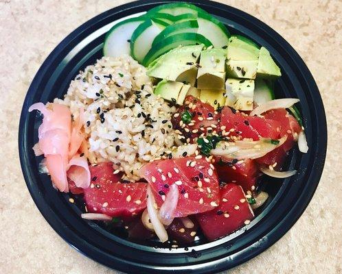 Ahi tuna poke bowl with brown rice, cucumbers, avocado, pickled ginger, and topped with furikake.