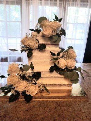 Traditional 3 tier naked wedding cake with fresh flowers.