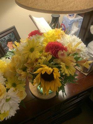 Sun flowers and carnations and yellow roses .