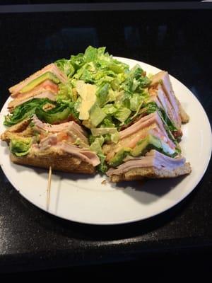 Turkey club with avocado and salad.