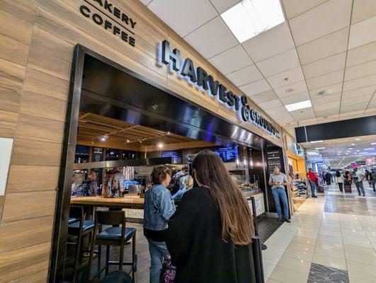 Harvest & Grounds storefront and line on a Thursday at 10:01 AM EDT. Located next to Gate D9 in Concourse D.