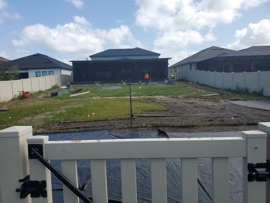 Backyard after fence and lanai enclosure projects. Landscaping, paver, turf and putting green projects begin.