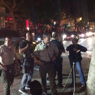 Police officers detaining my husband against his will in front of a crosswalk he tried to cross.