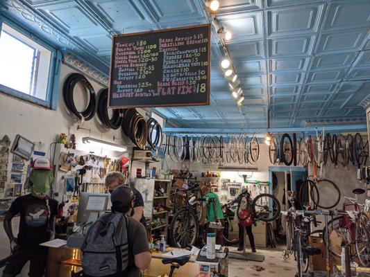 Photo of the interior of the shop behind the counter, with bike mechanics working on bike repairs