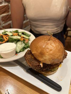 Spicy chicken sandwich with side salad.