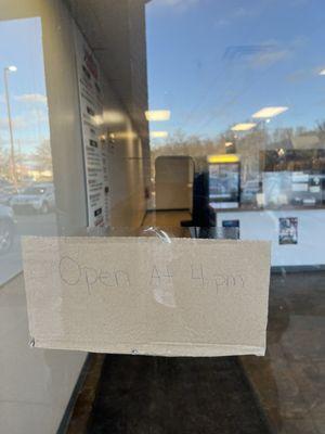 Card board box on the door that says open at 4pm