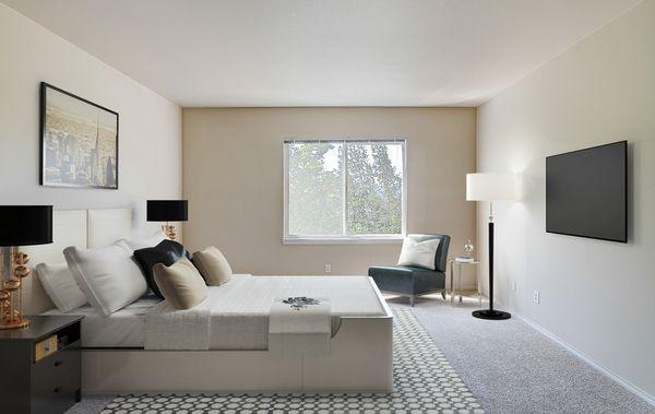 Staged and carpeted bedroom with window.