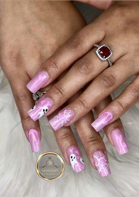 These nails feature a playful pink Halloween design with cute white ghosts and intricate spider webs, perfect for a spooky yet stylish look.