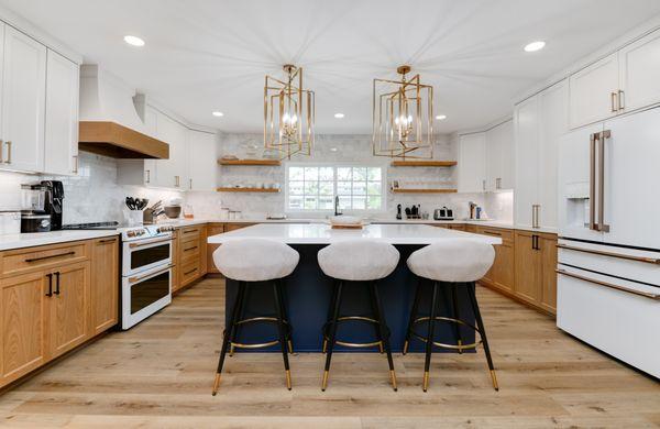 Kitchen with warm wood cabinetry, navy island, marble countertops, brass fixtures, and high-end appliances for timeless sophistication.