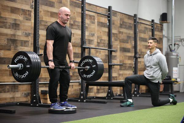 Matthew executing a deadlift, guided by coach Dario