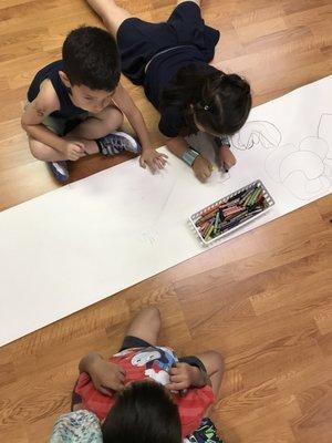 Children gathered around on the floor to express their thoughts through drawing together