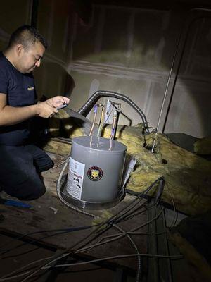 Julio installing a 6 gallon water heater in ceiling of business