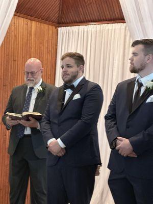 Pastor, groom, best man front of chapel