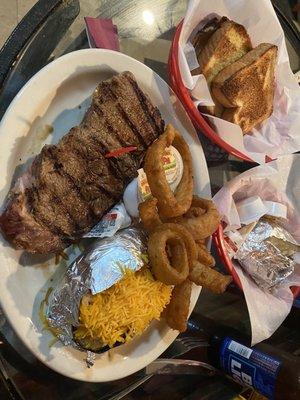 Pete 's Ribeye, onion rings, and baked potato