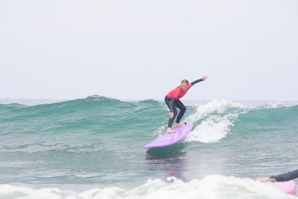 Female student dropping into a wave during Summer Surf Camp!