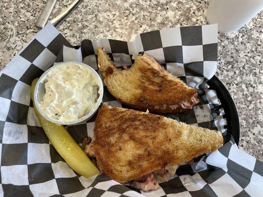 Reuben sandwich with potato salad and pickle spear.