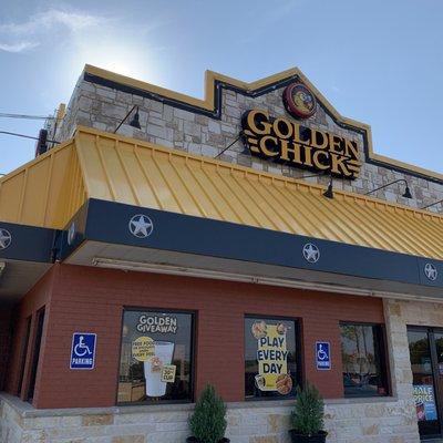 Golden Chick restaurant from street side with promotional banners in the window.